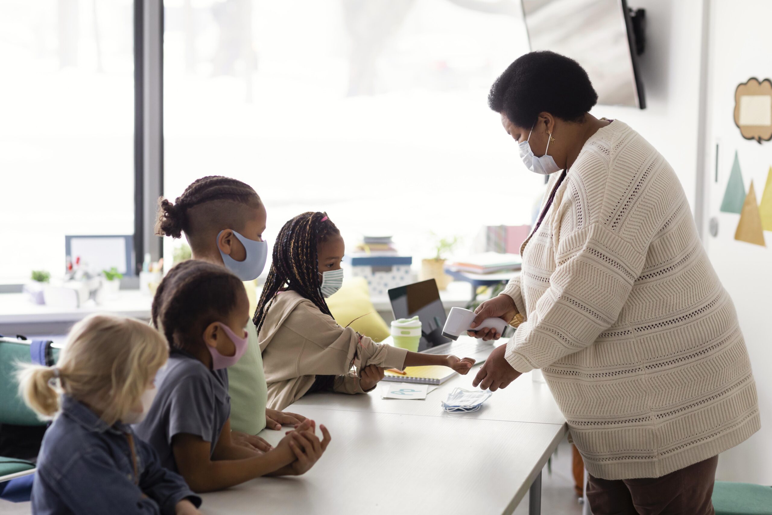 Female Teacher Checking Temperature Each Student Scaled